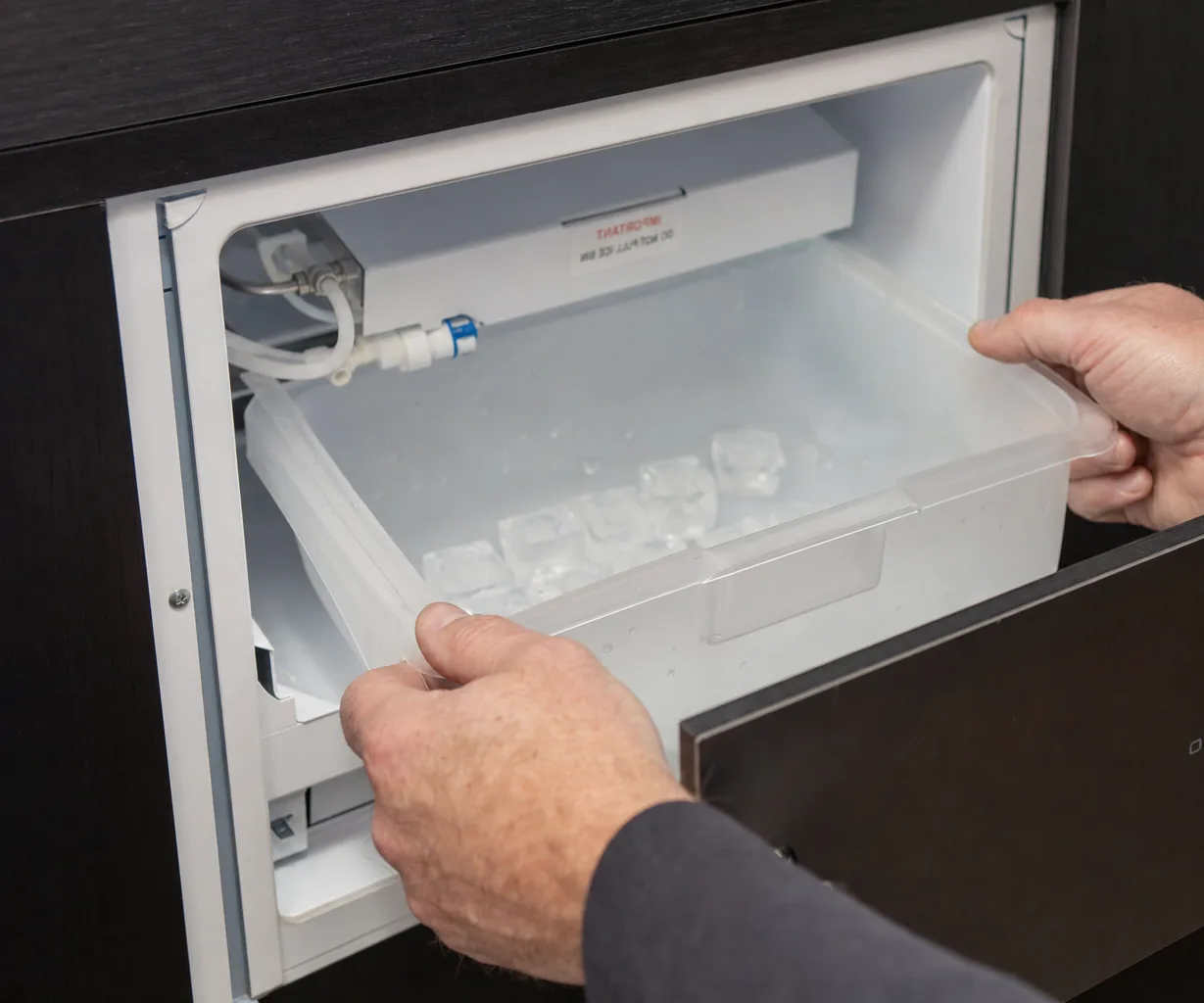 Technician servicing a built-in ice maker mid-repair
