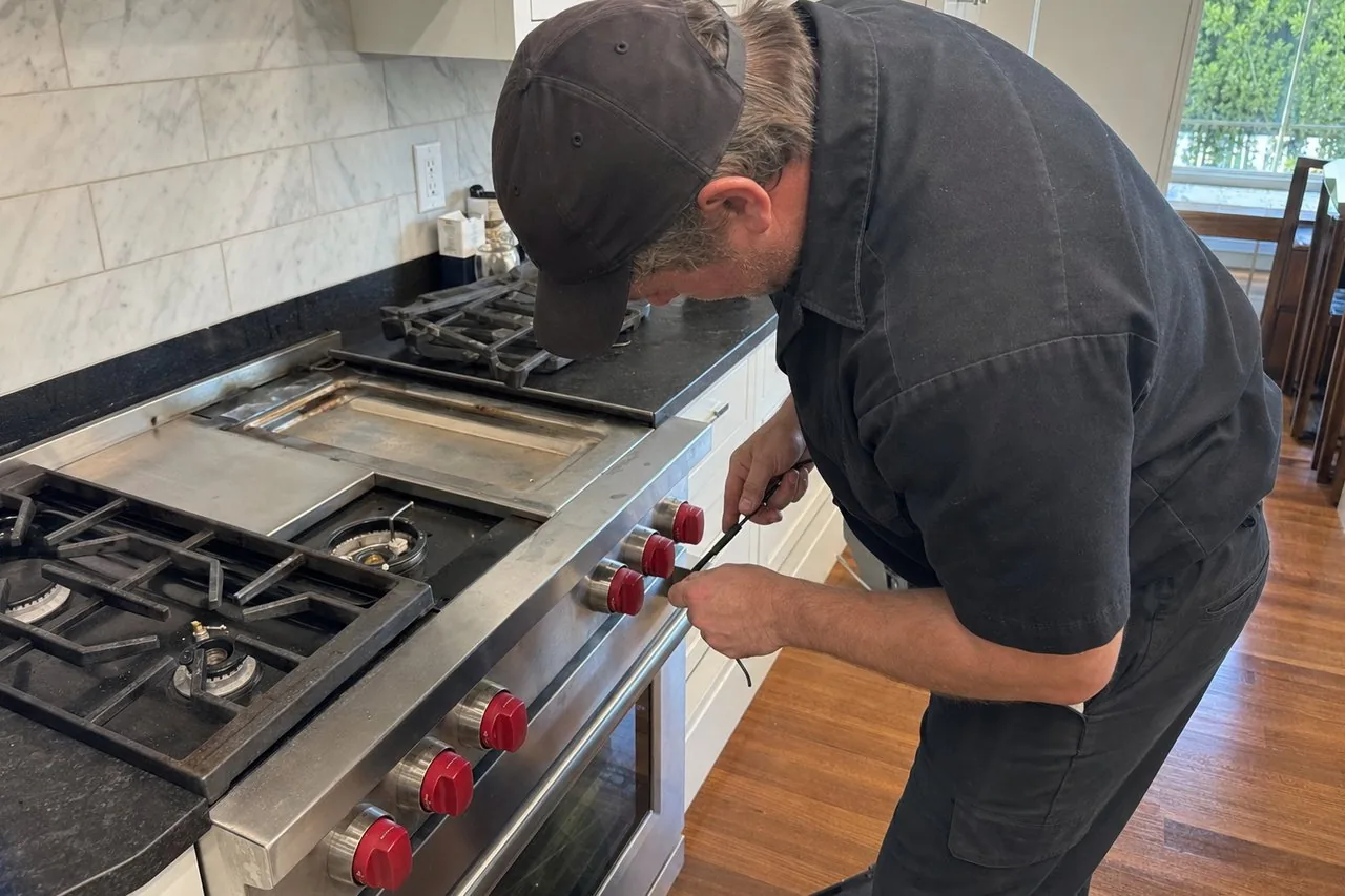 Technician servicing a stainless Wolf range up close